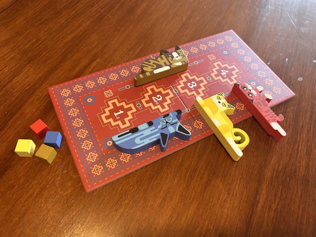 Four cat tokens laying on the bidding rug.