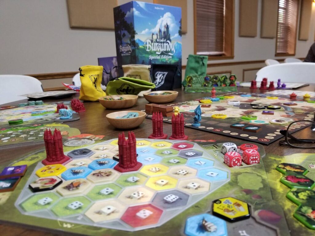 The full set up, set out on the table. The 3D printed castles stand tall above the boards, and the game box looms in the background.