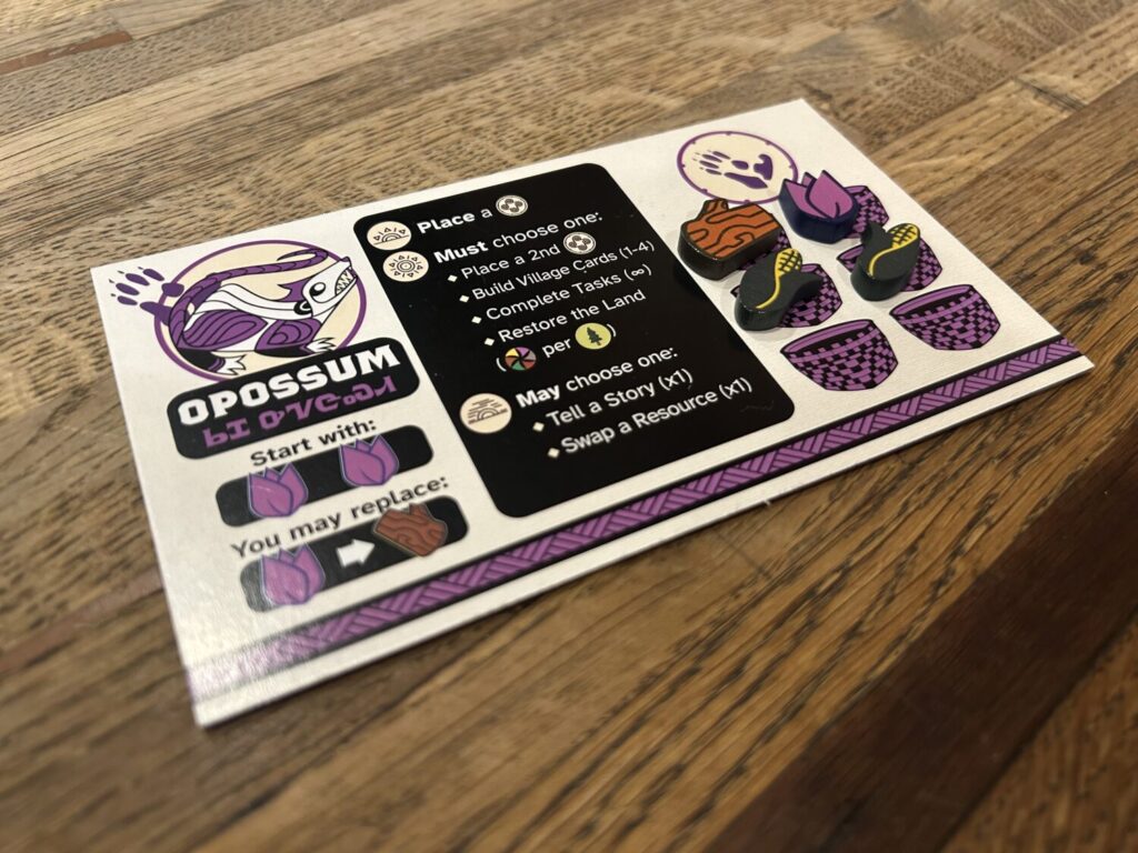 A white rectangular player board for the Opossum, featuring a prominent and stylized character illustration in the upper left corner. To the right, four screen printed wooden tokens representing different resources sit on printed basket icons.