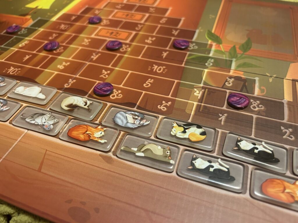 Two rows of clear plastic tiles with cat illustrations on top, sitting on a board decorated with a pyramid.