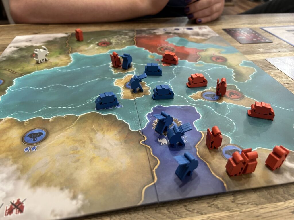 A board, divided in regions. Many are occupied by boat or soldier meeples.