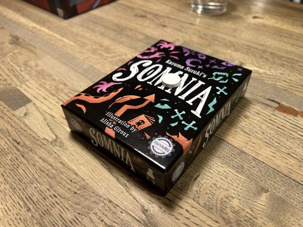 A black box on a wooden table. The cover is divided into four color sections.